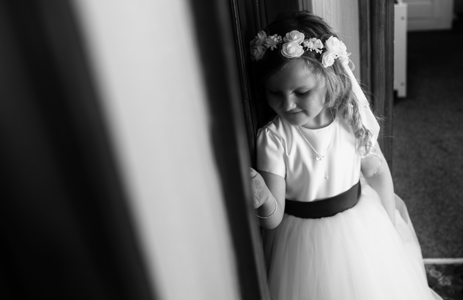 Black and white photo of the little bridesmaid waiting for the bride to get into her dress