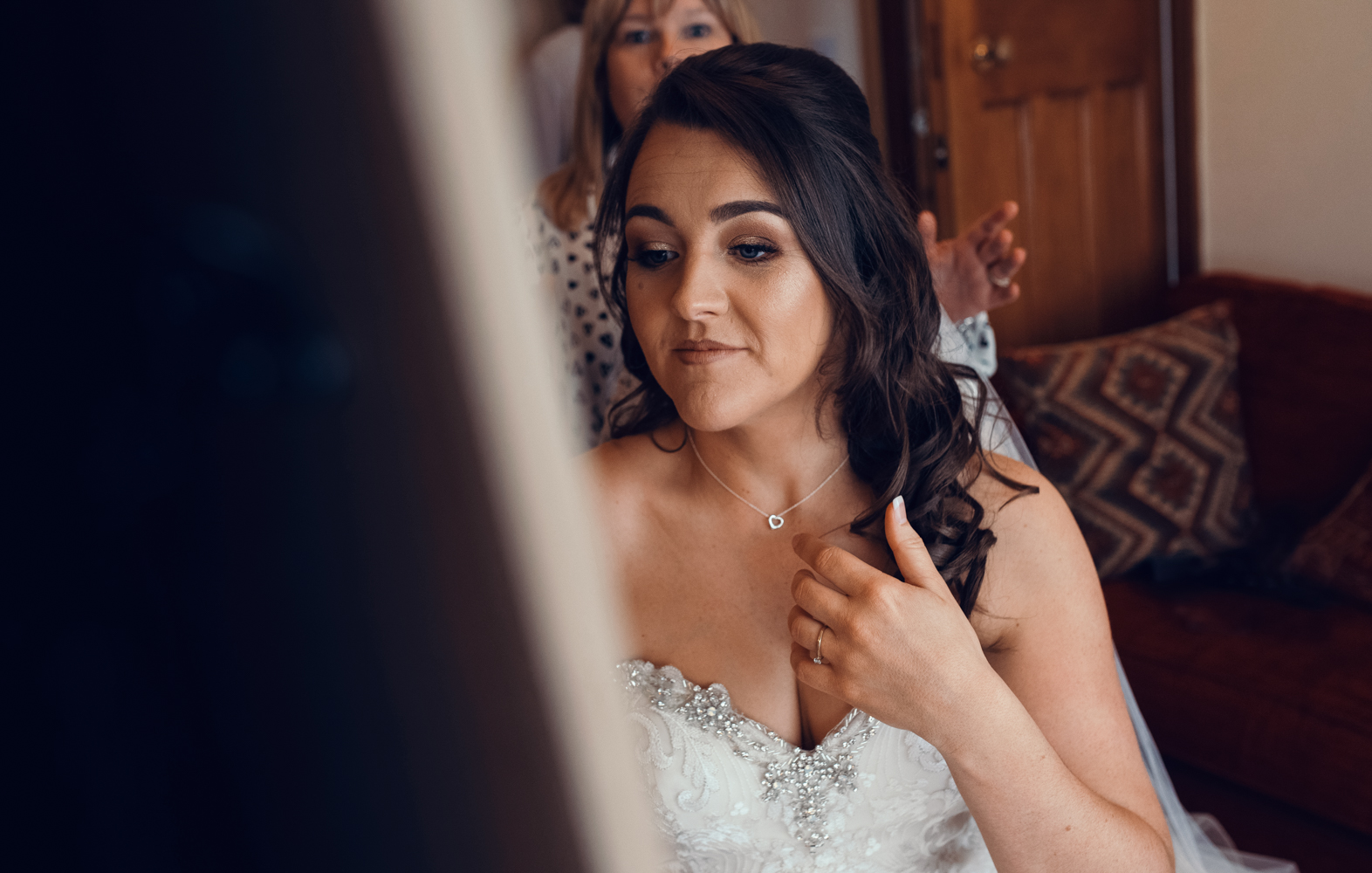 Photo of the bride admiring her hair in a mirror during morning bridal preparations