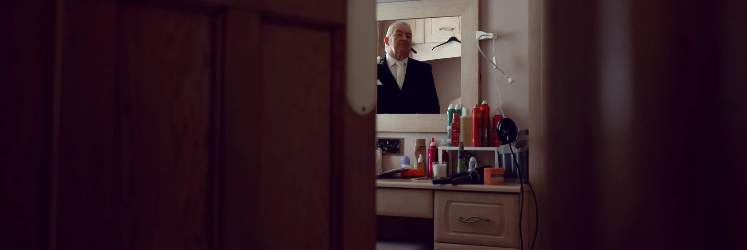 The brides father checking his look in a mirror