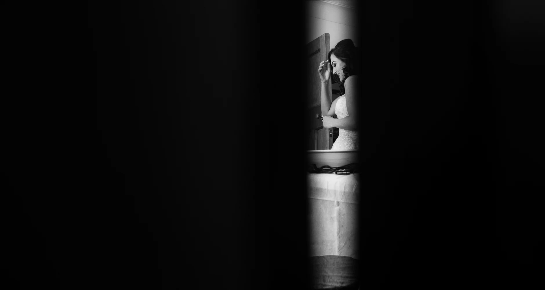 Black and White photo of the bride through the partly open door