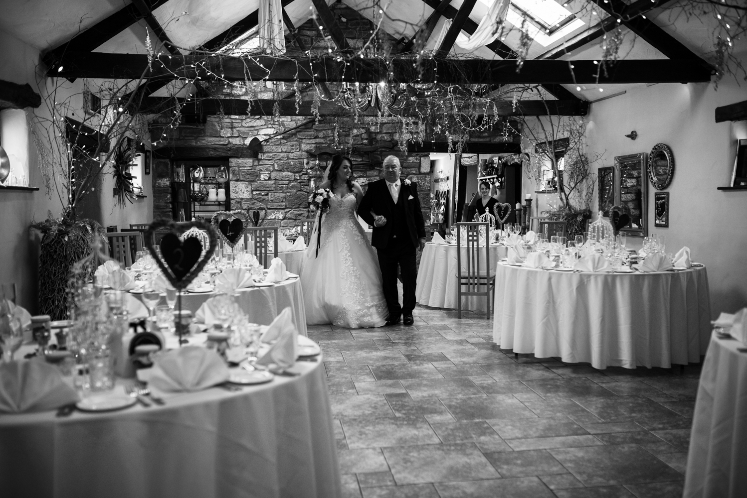 Black and white photo of the bride and her father walking towards the registrars