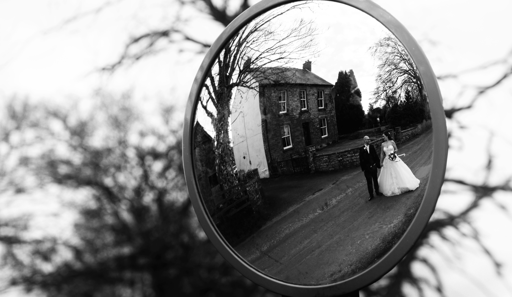 A black and white photo of the bride and groom reflected in a mirror