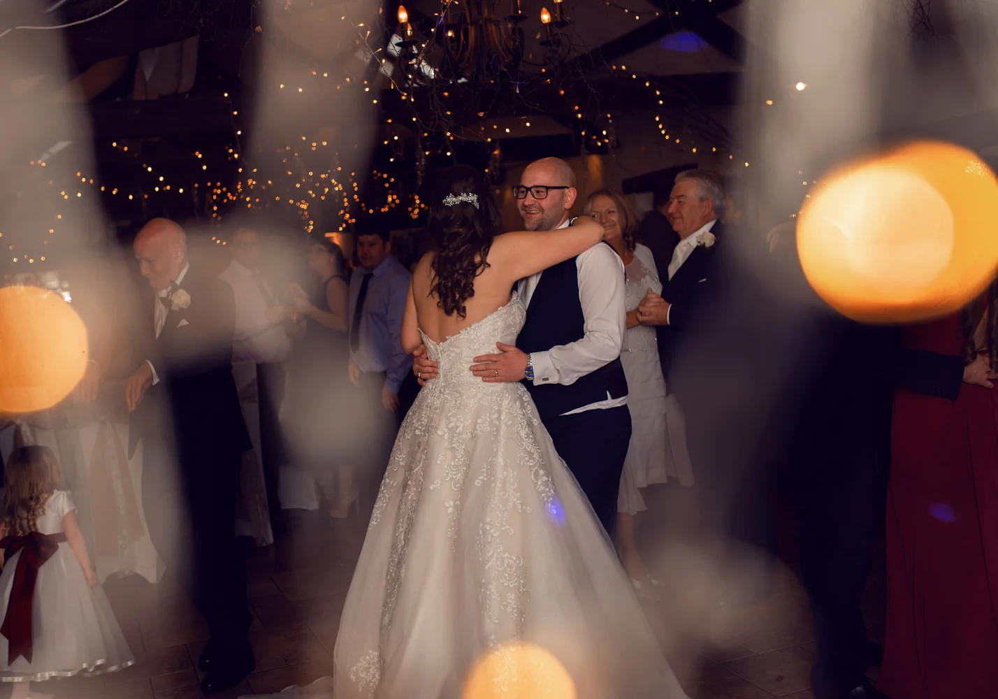 A photo of the bride and groom during the first dance taken though fairy lights