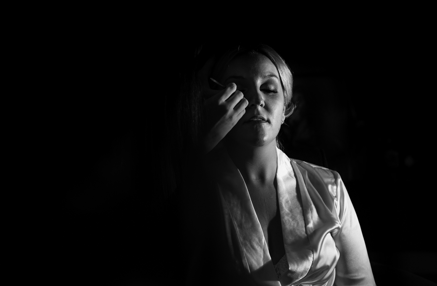 A black and white photograph of the bride during her makeup 