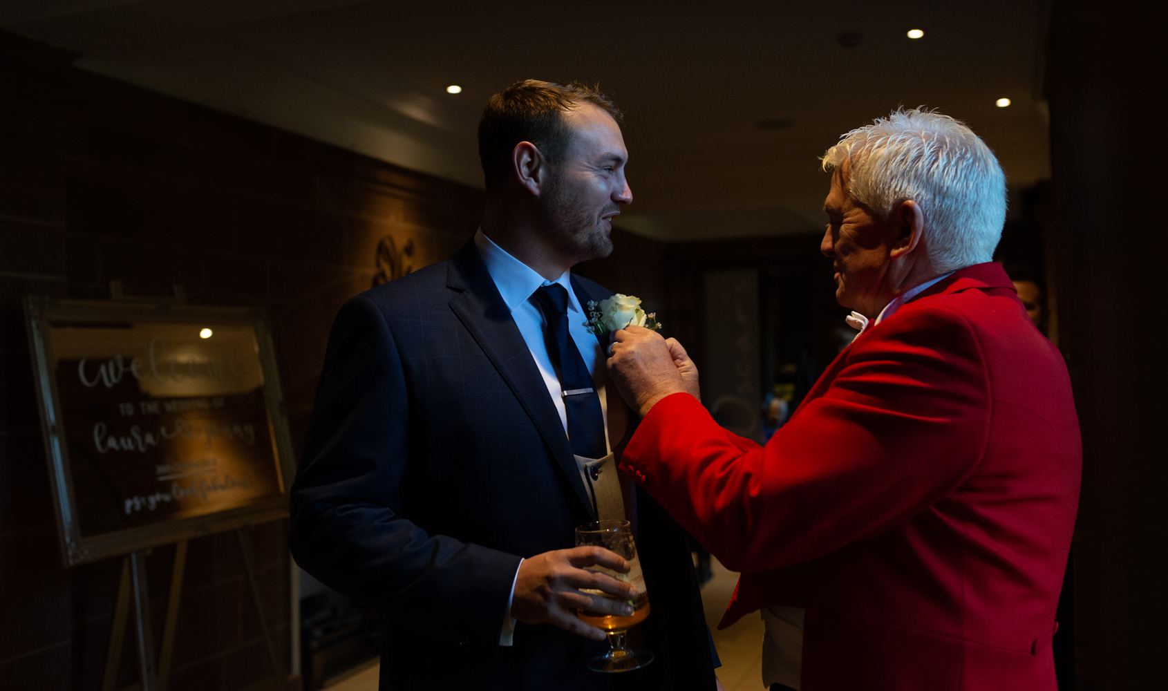 One of the best men being assisted to put his button hole on by the toastmaster