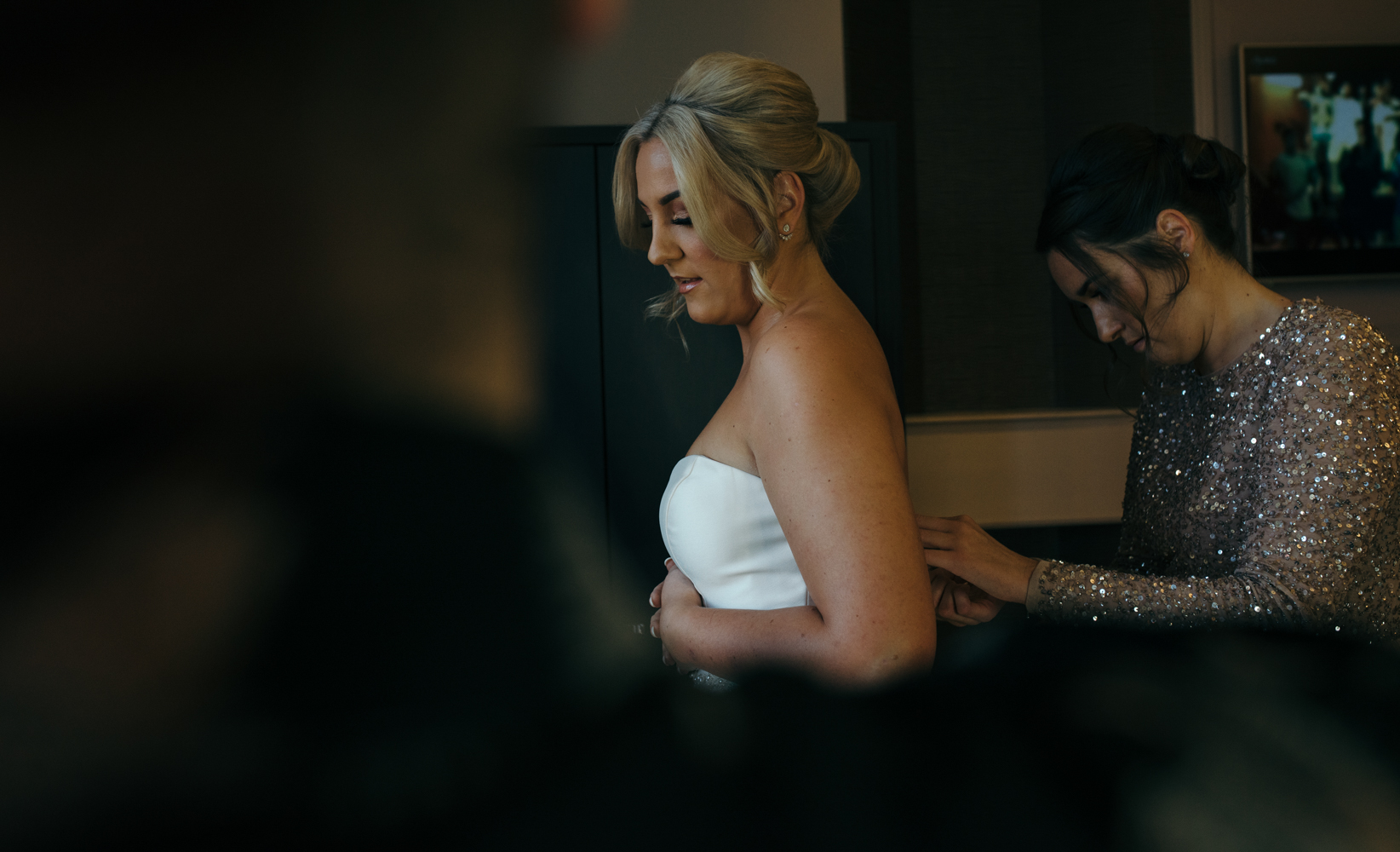 The bride being fastened into her wedding dress