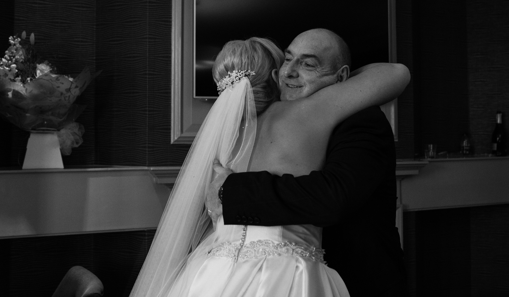 Black and white photo of the bride and her father having a hug when he sees her for the first time