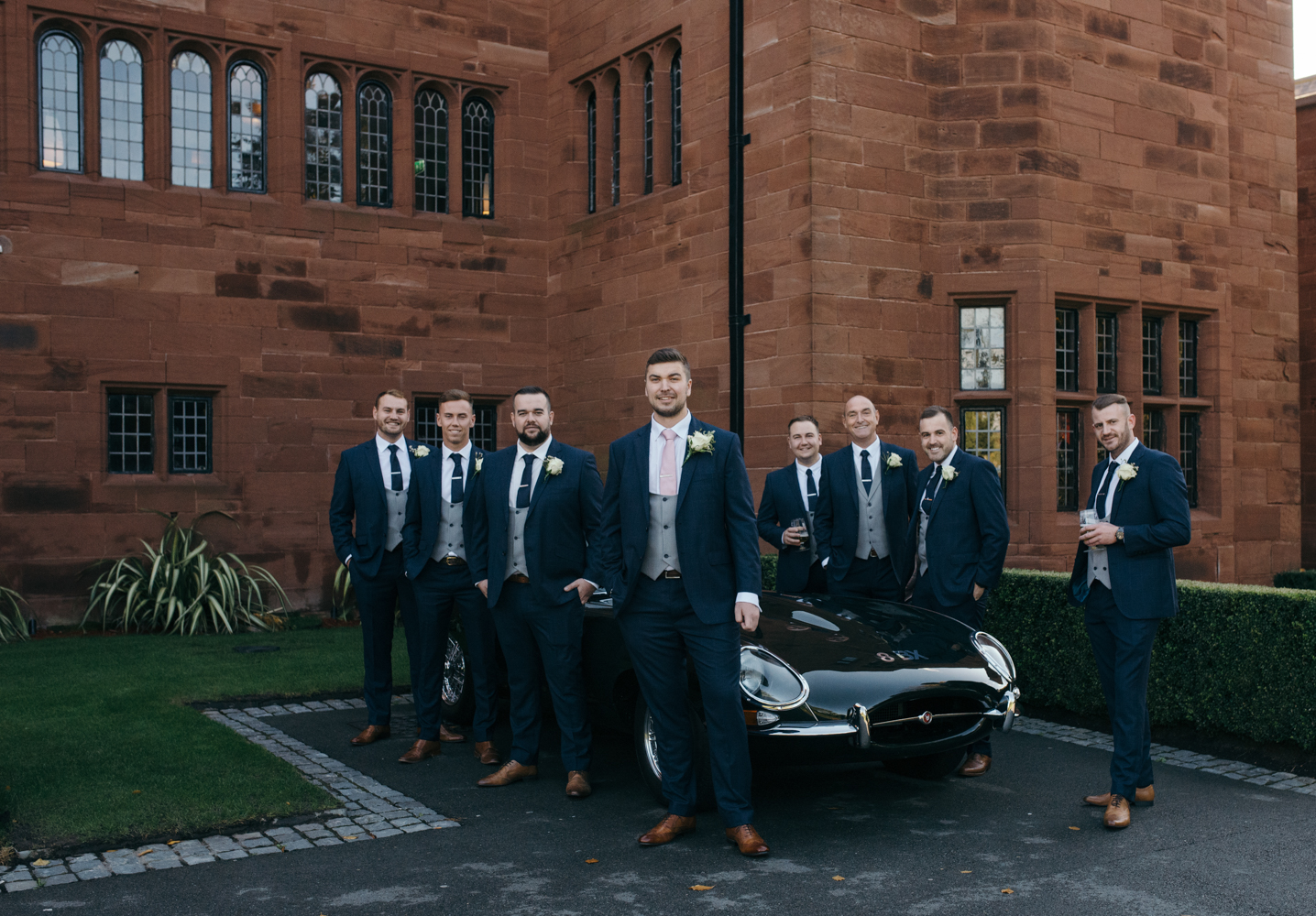 All of the boys standing outside around a fabulous vintage e-type jaguar car