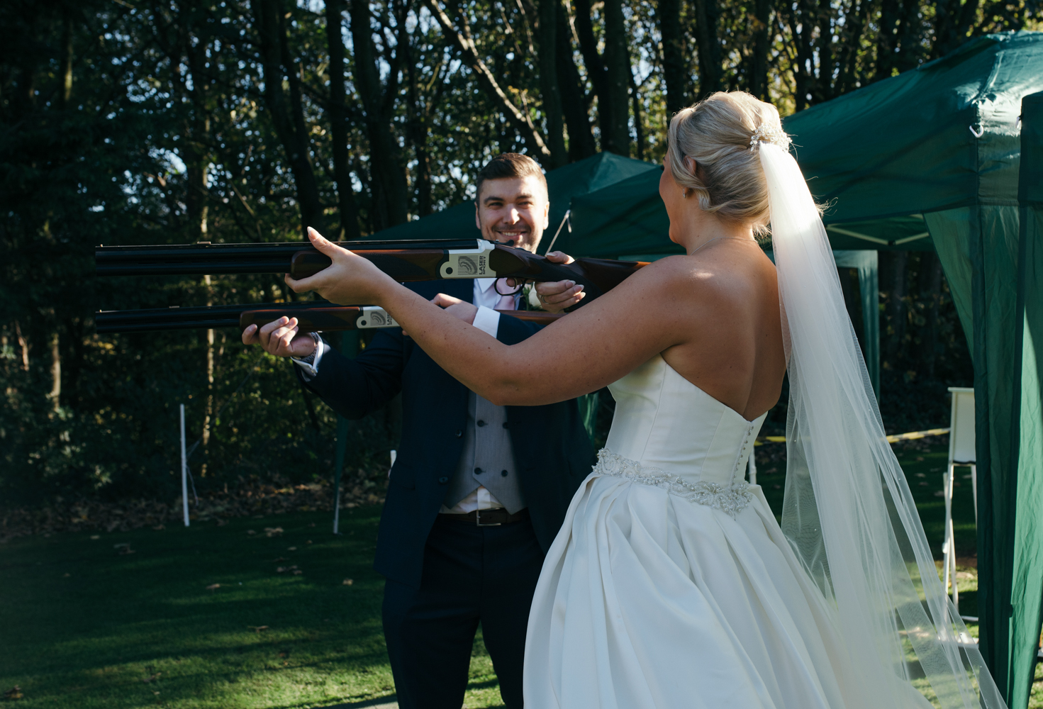 The bride and the groom both having a try at laser clay pigeon shooting