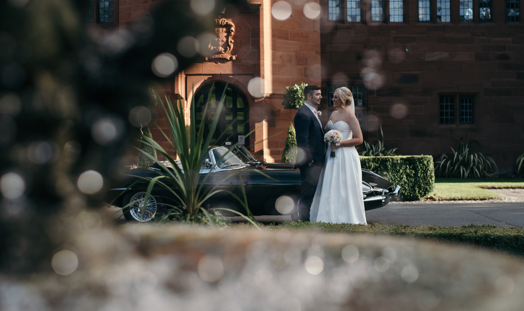 The bride and groom outside Abbey House Hotel standing by the classic e-type jaguar