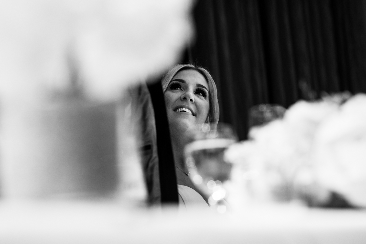 Black and white photo of the bride looking up at the groom during his speech