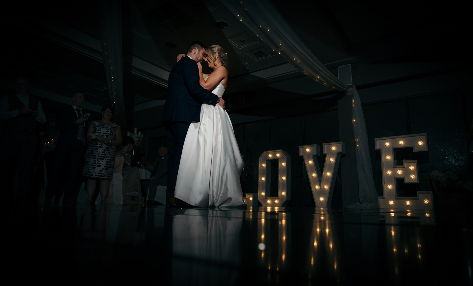 The bride and groom during their first dance featuring the large light up love letters