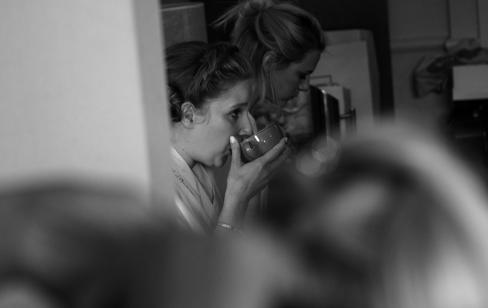 Black and white photo of a bridesmaid enjoying a nice cup of tea during morning preparations