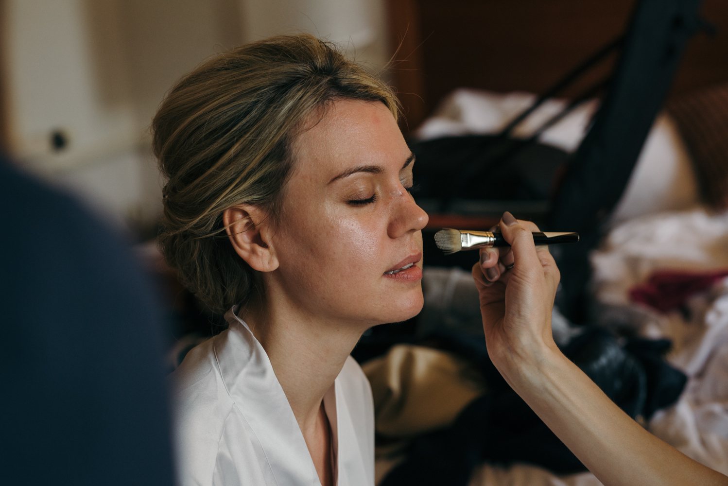 The bride having her makeup applied during durning bridal preparations