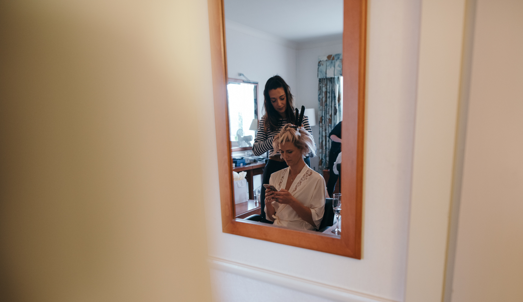 A bridesmaids reflection in a mirror during morning bridal preparations