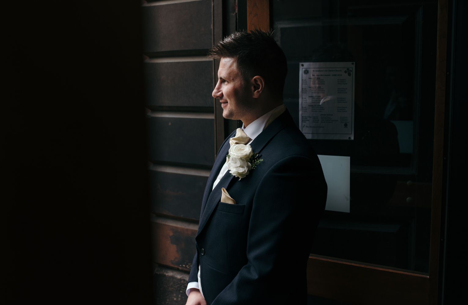 The groom solo portrait standing in the church doorway