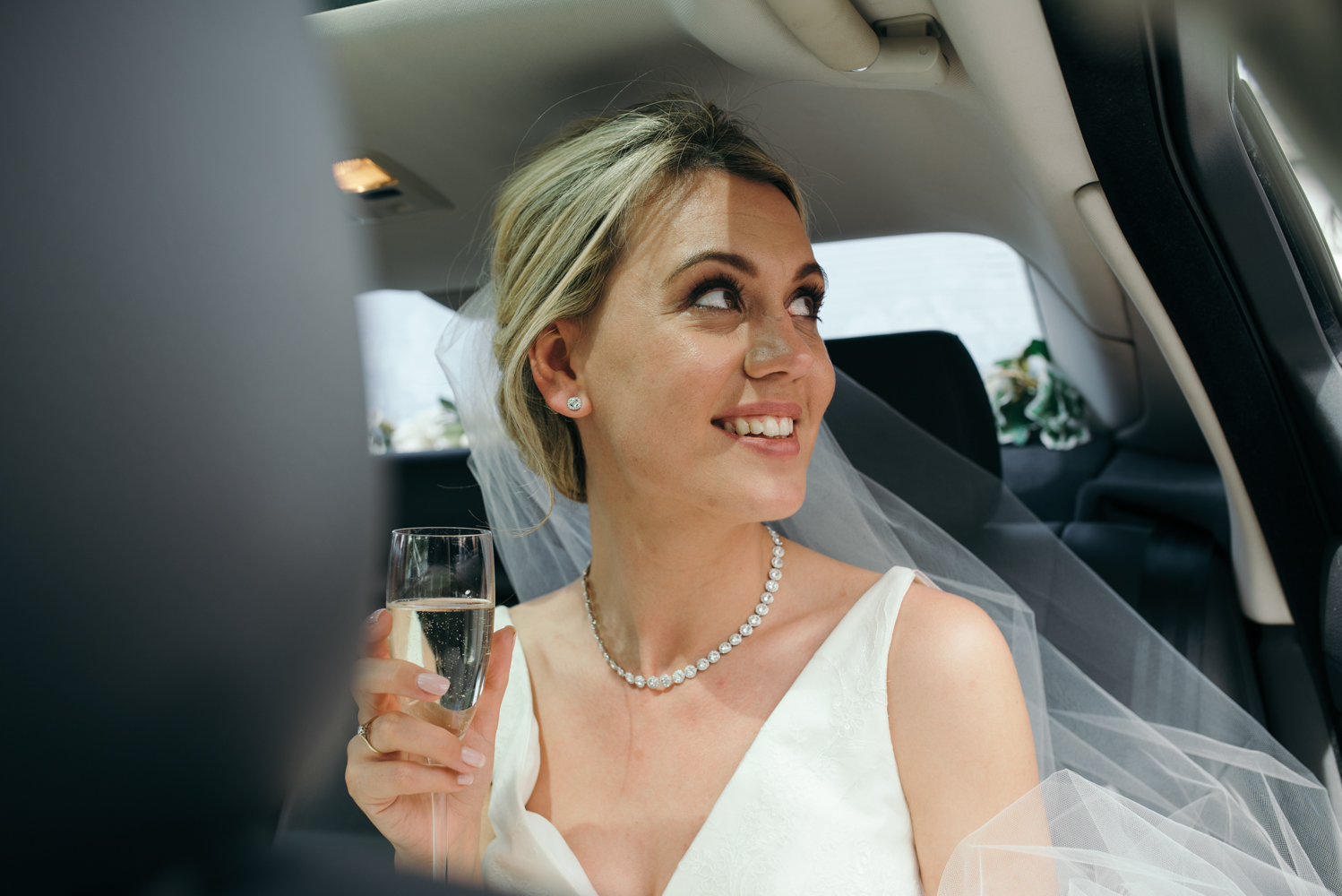 The bride enjoying a glass of bubbly as they arrive at Low Wood Bay Hotel