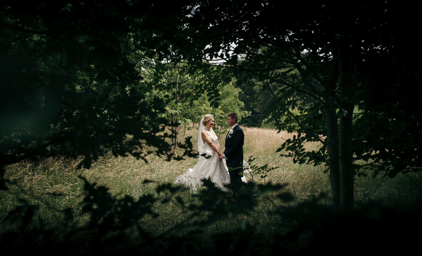 The bride and groom standing in a field during the couples portrait photo shoot