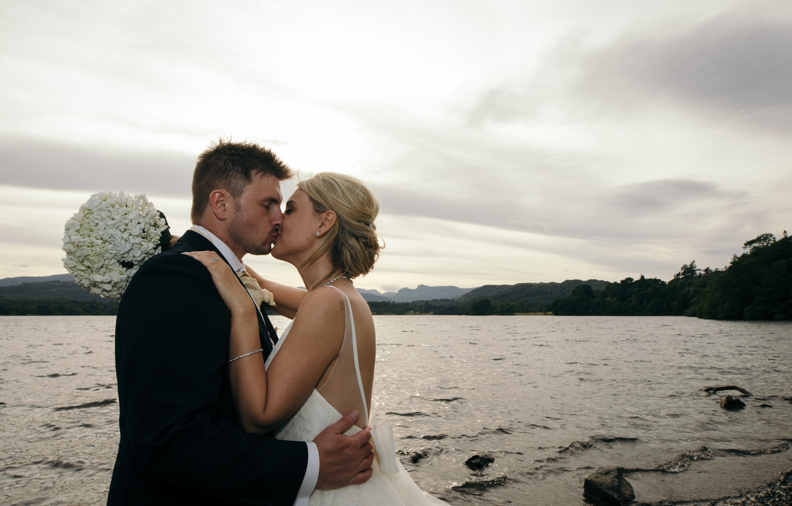 A sunset portrait of the bride and groom taken down by the boat jetty on Windermere