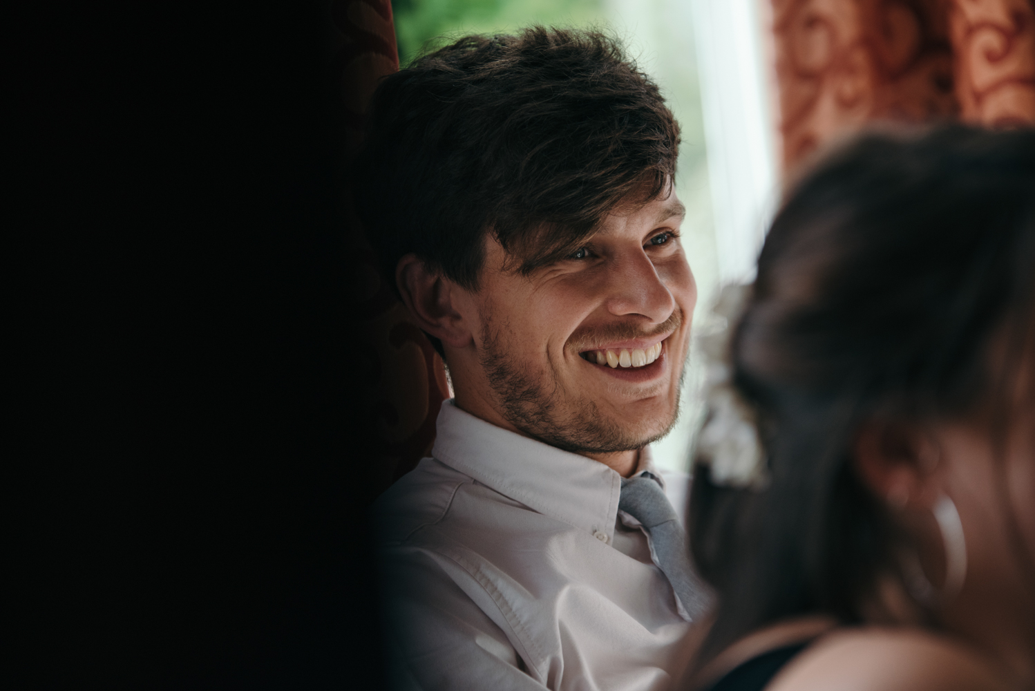 A male wedding guest having a laugh at something the groom said in his speech