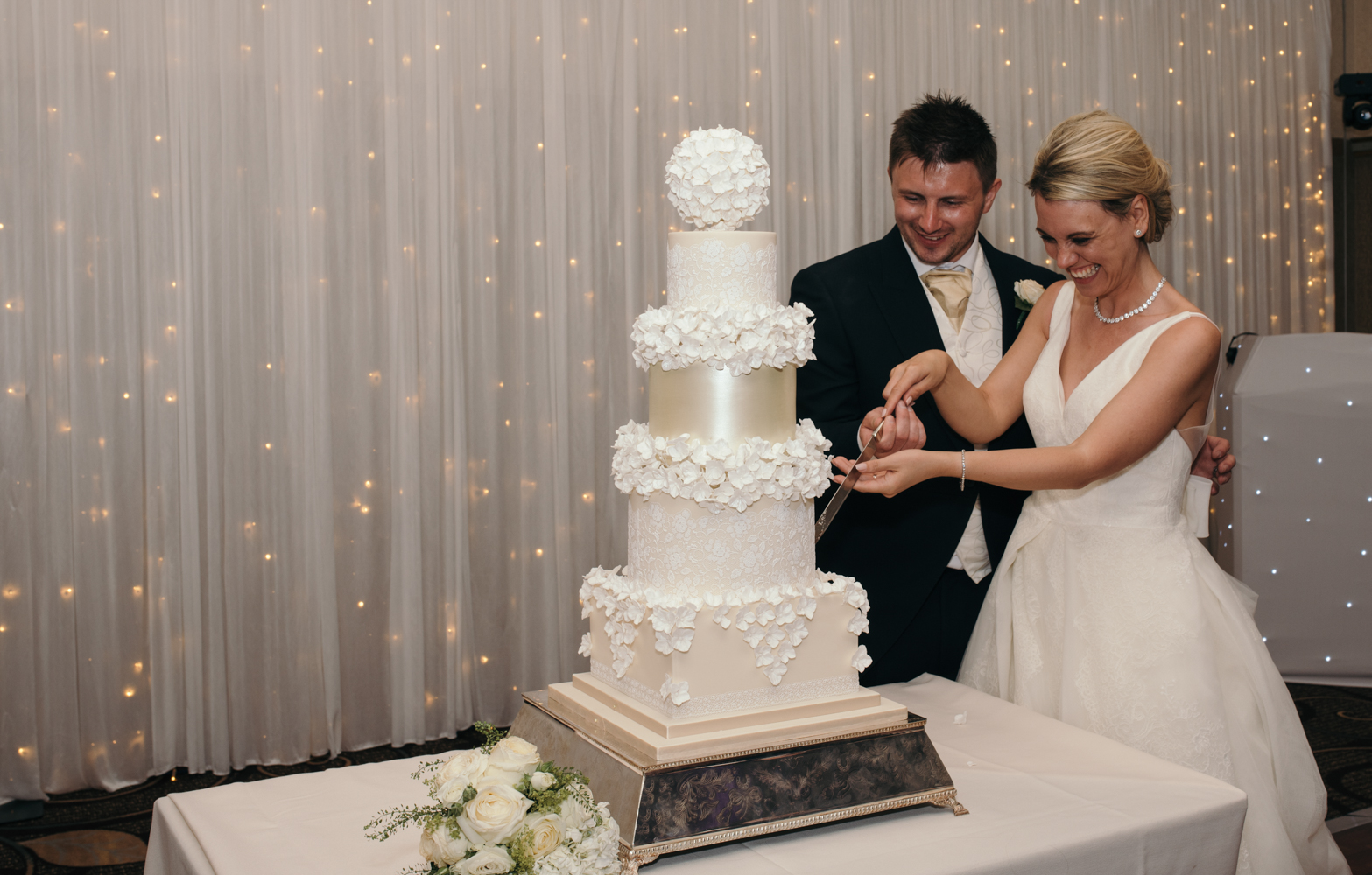 The bride and groom giggling whilst cutting the wedding cake