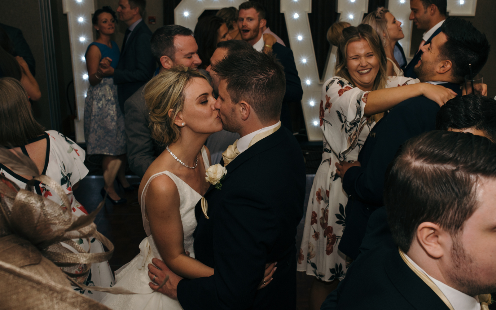 The bride and groom having a kiss on the dance floor whilst everything else is madness around them