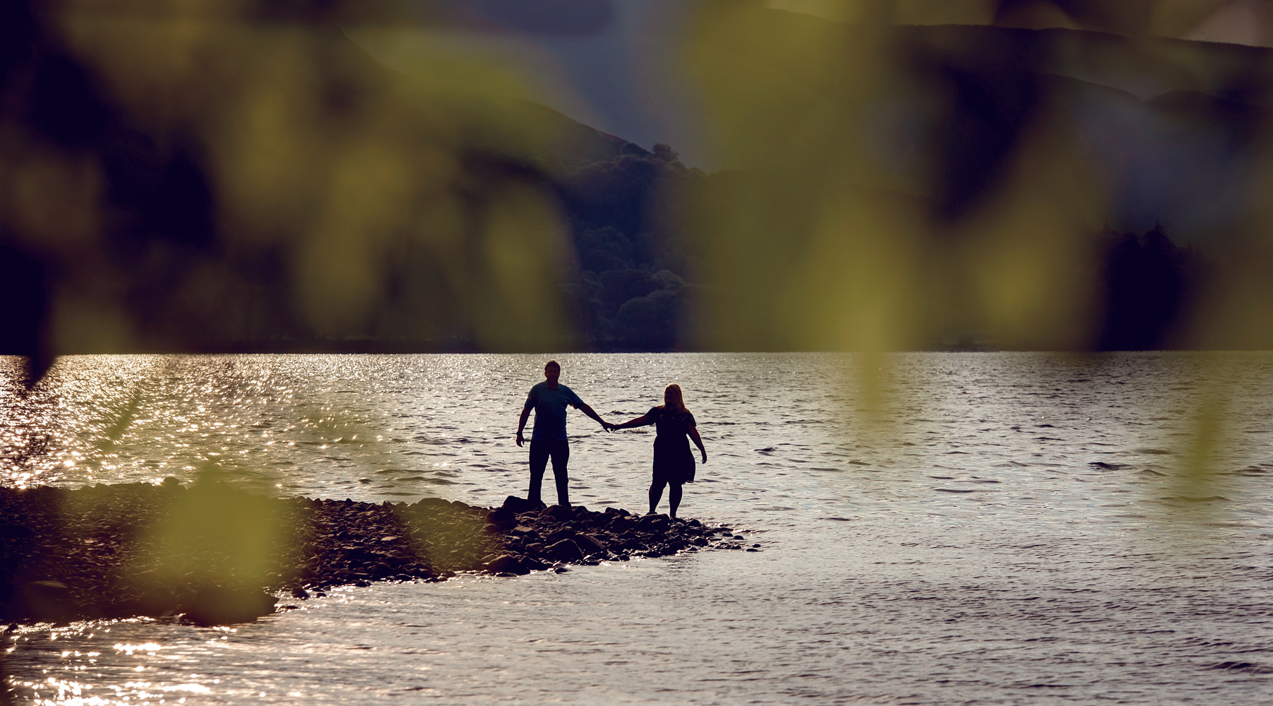 Pre shoot - A very distant and wide angle photo of a couple standing at the waters edge Derwent water in the Lake District