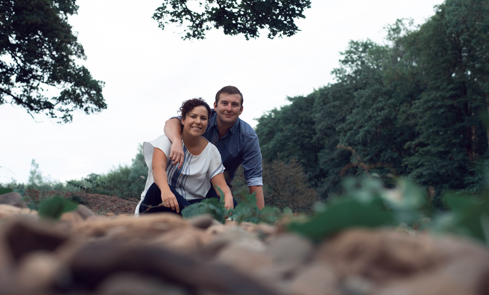 Pre shoot - portrait of a couple sitting on the stones by a river near Lanercost Priory Cumbria