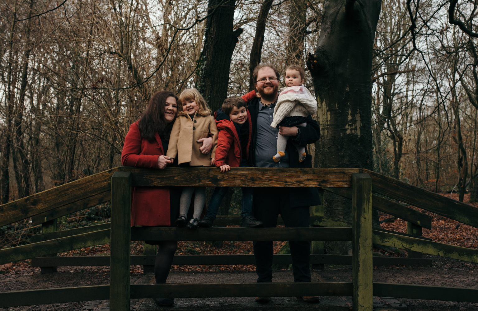 Another family group photograph standing on a bridge in the woods