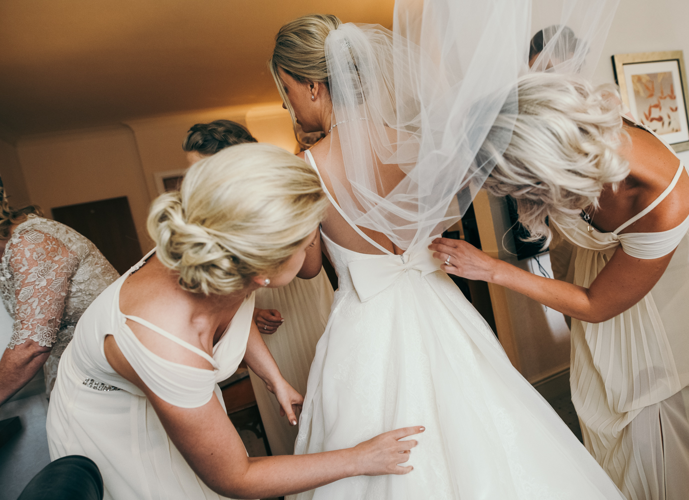 A bride being helped into her wedding dress during morning bridal preparations
