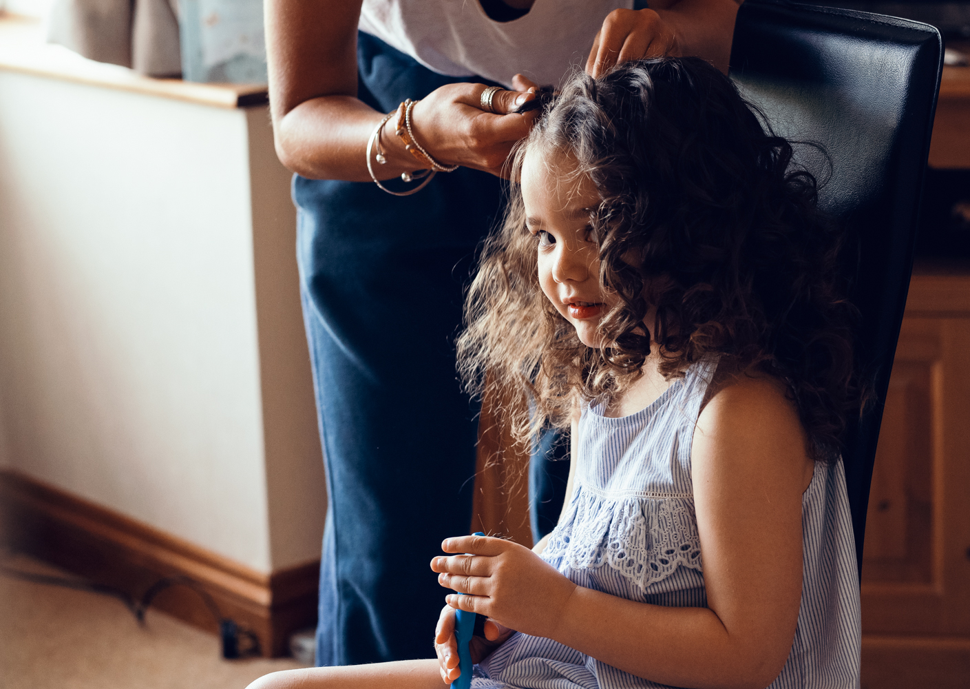 A little bridesmaid having her hair done during morning bridal preparations