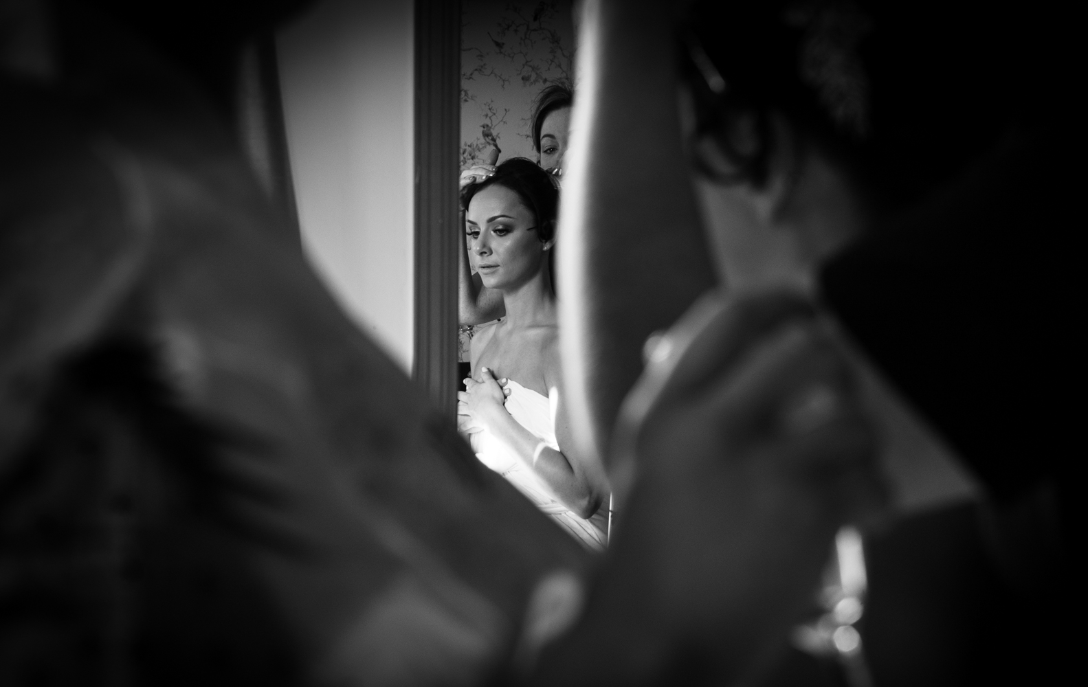 A black and white photograph of a bride getting into her dress during morning bridal preparations