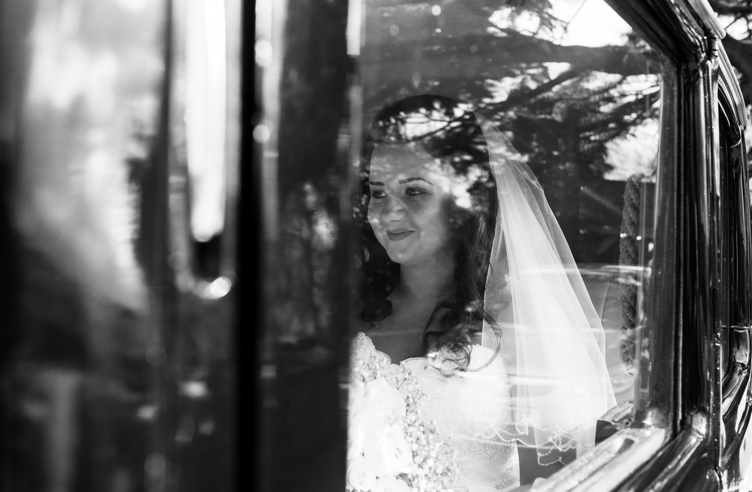 A black and white photograph of the bride sitting in the car prior to her wedding ceremony