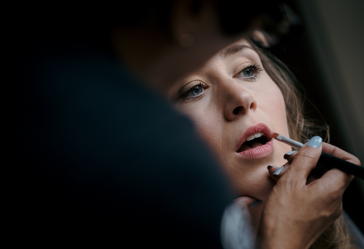 A bride having her lipstick applied during morning bridal preparations