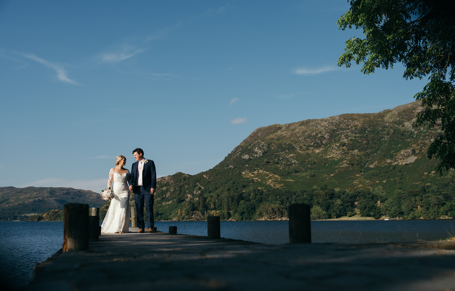 A bride and groom walking back along the jetty Inn on the lake