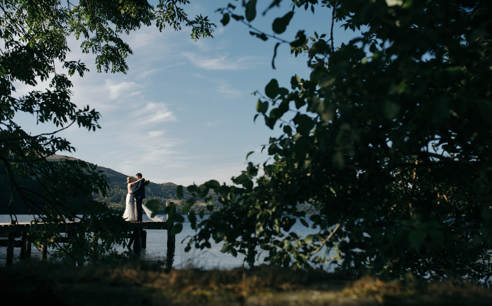 A bride and groom standing on a jetty Ullswater Lake District