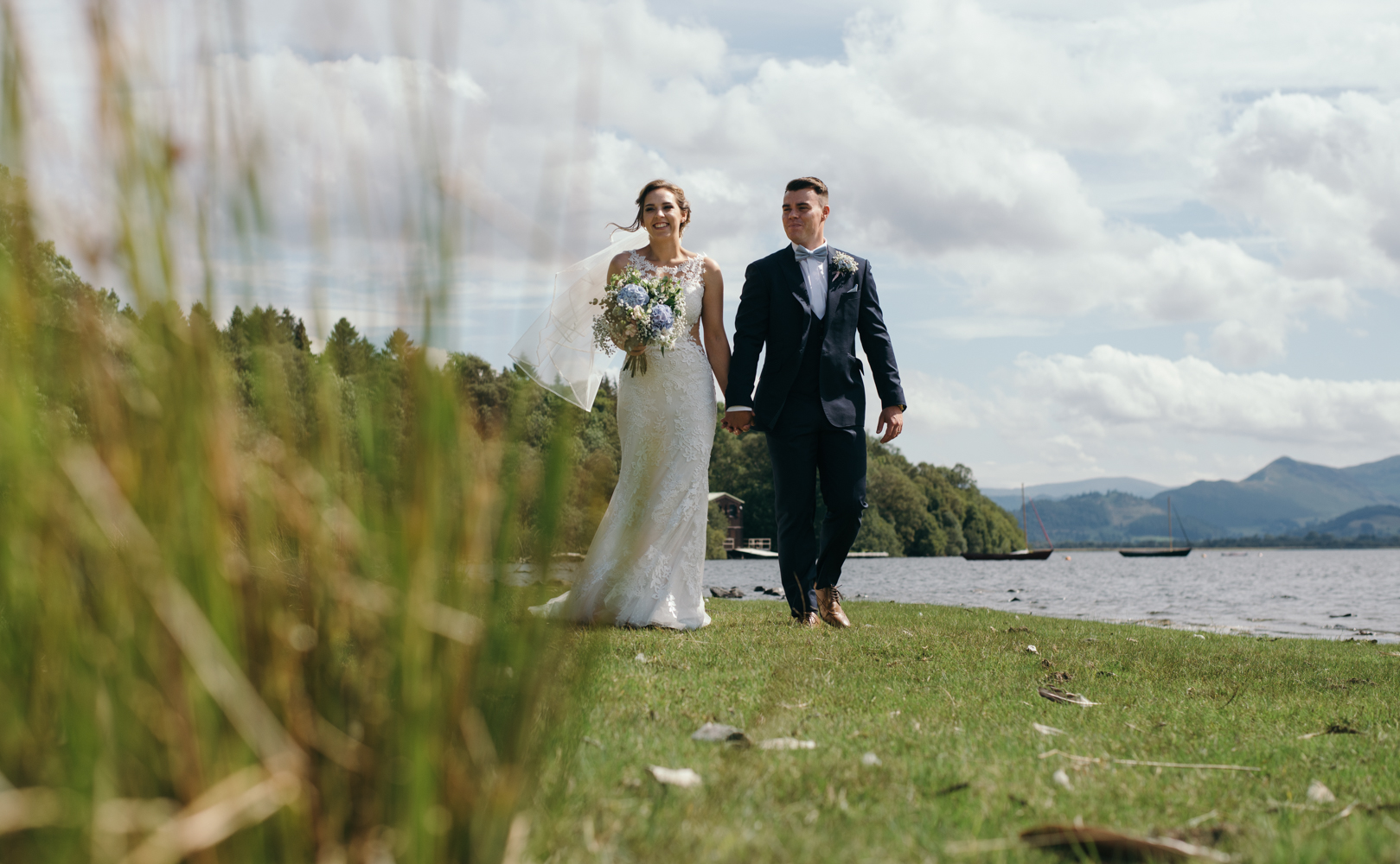 A bride and groom walking along the lake side