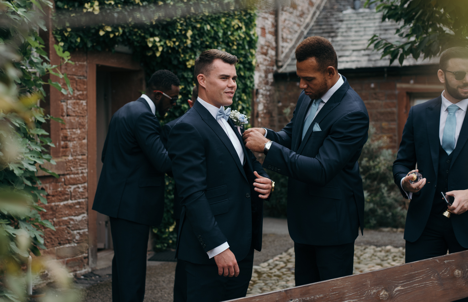 A groom getting some help with his button hole