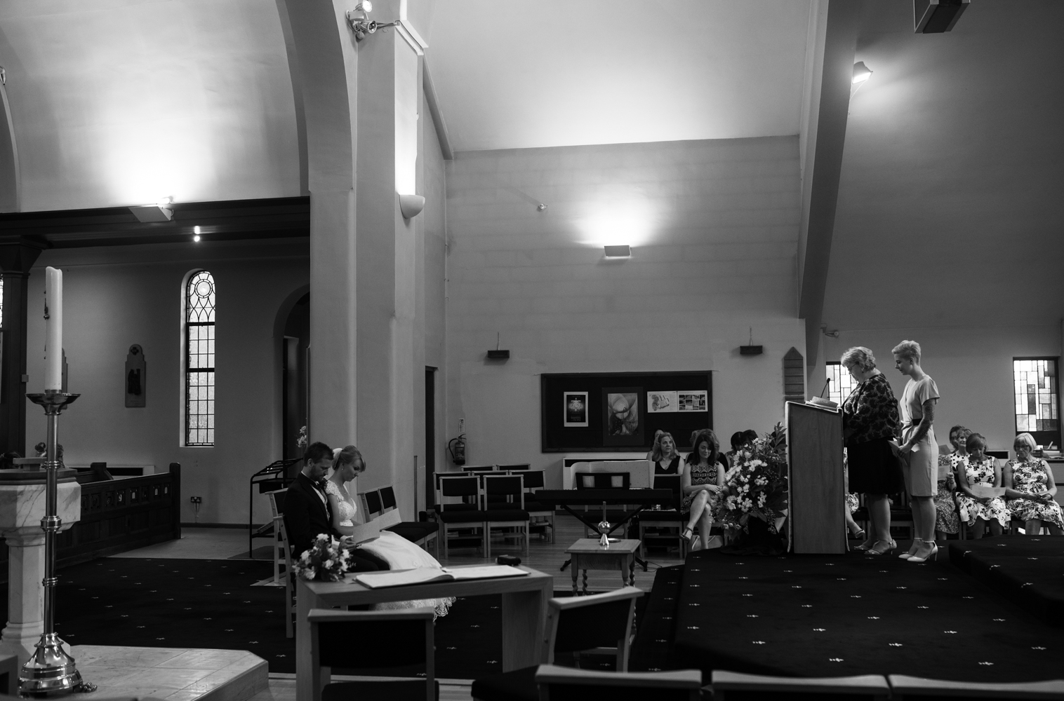 A black and white photo of the bride and groom sitting during the ceremony