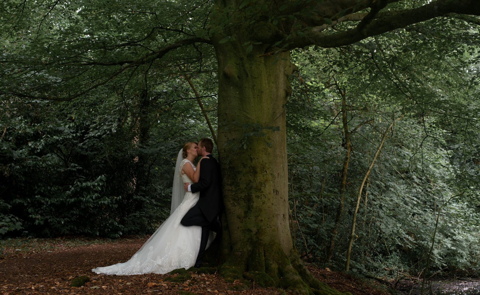 The bride and groom standing in the woods