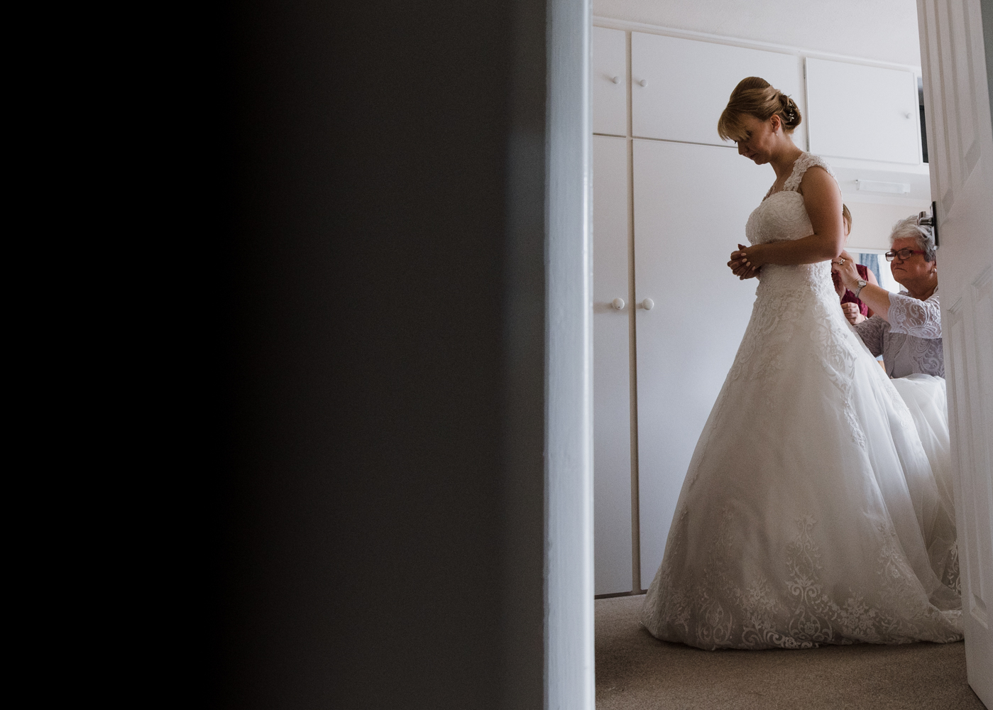 The bride being helped into her wedding dress