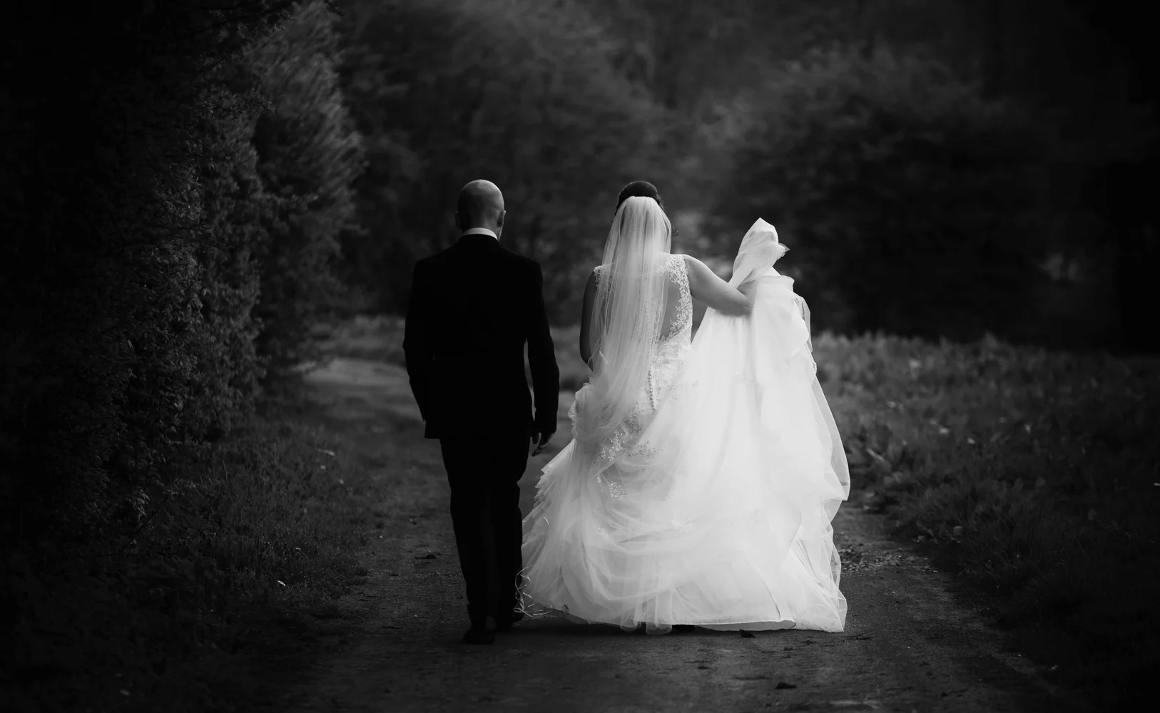 A black and white image of the bride and groom walking away from the camera.jpg