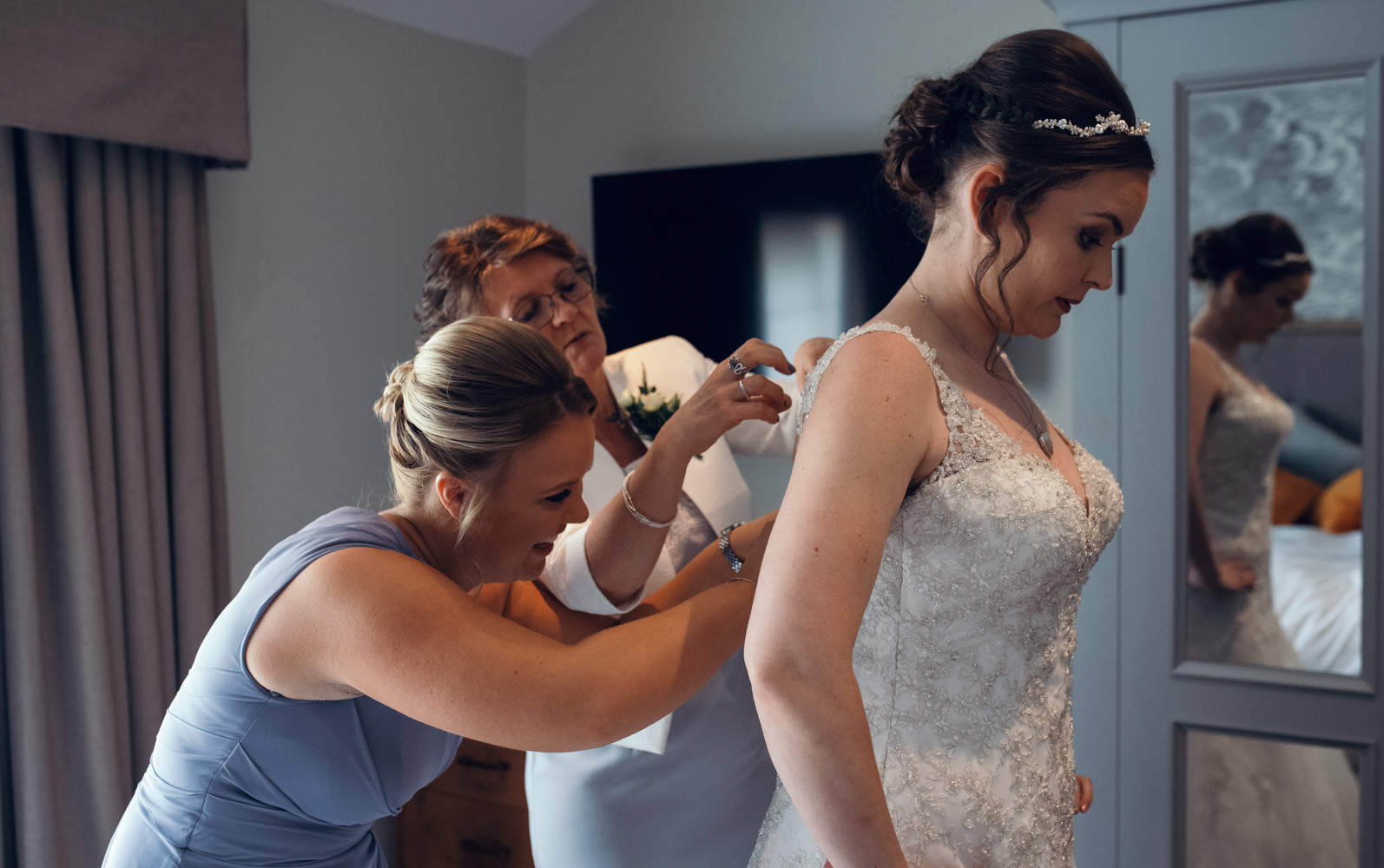A bride bring helped into her wedding dress