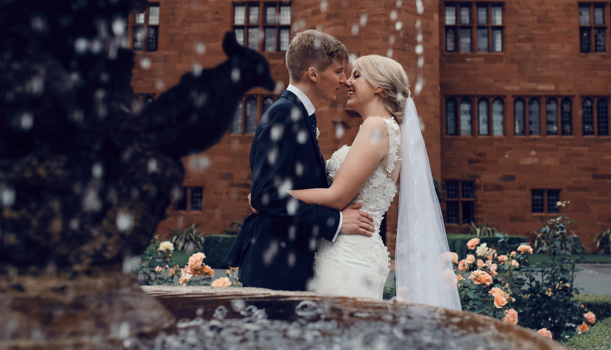 A bride and groom in front of a fountain at Abbey House Hotel