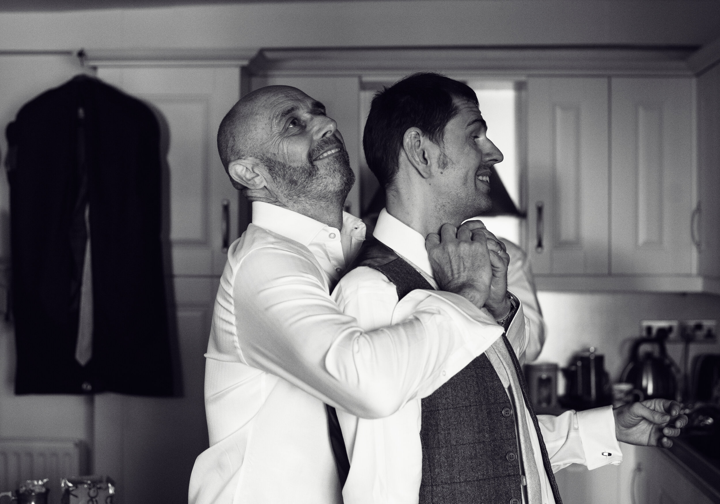 The best man helping a groomsman with his tie