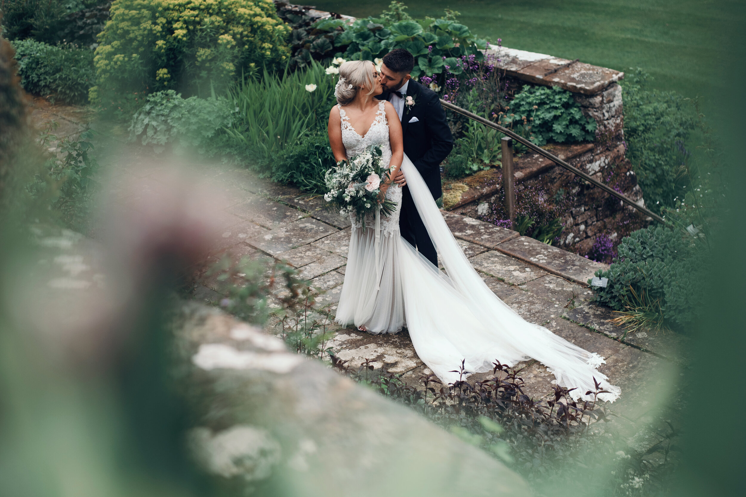A bride and groom kissing in the sunken garden at Askham Hall