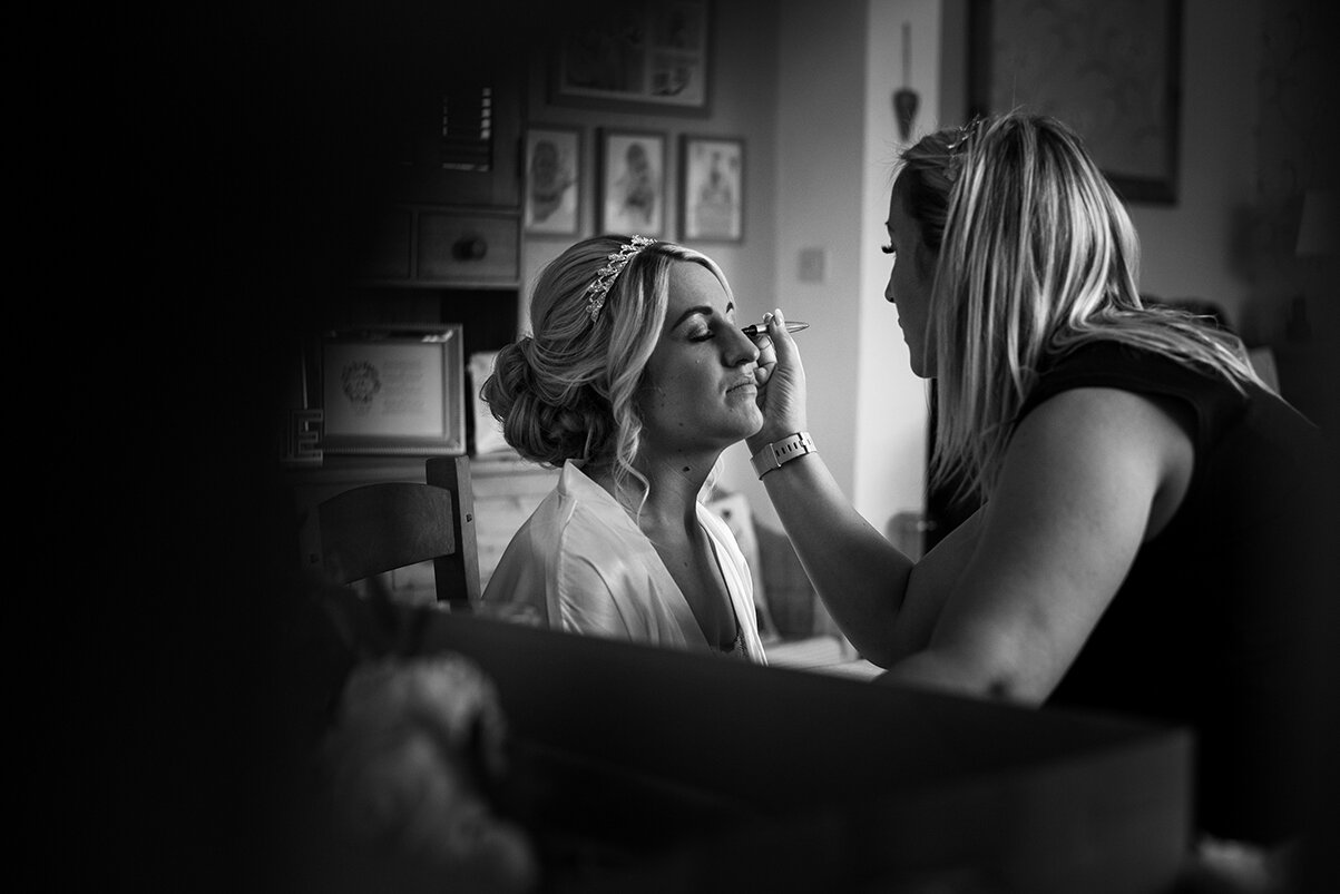 Black and white photo of the bride having her makeup done