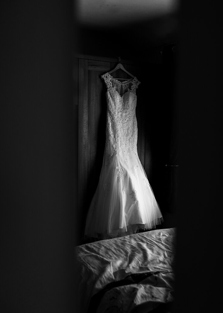 The brides dress hanging in the bedroom