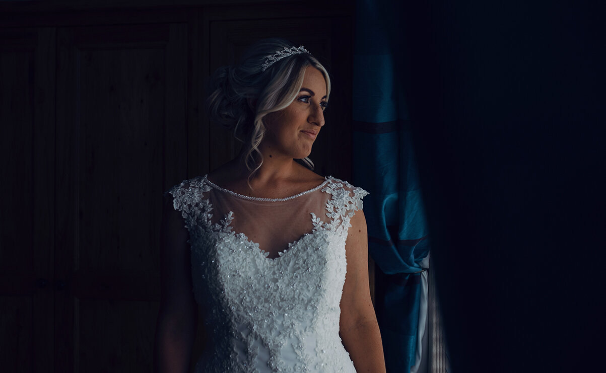 The bride in her dress standing in the window