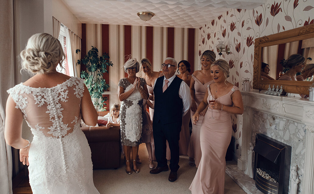 The bridesmaids and parents first glance at the bride in her wedding dress